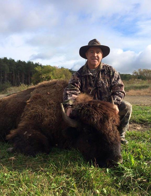 Man posing next to bison he hunted