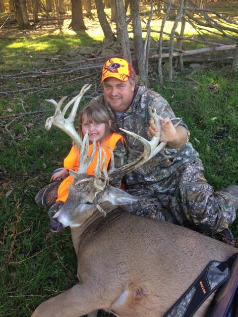 Father and child posing with whitetail deer