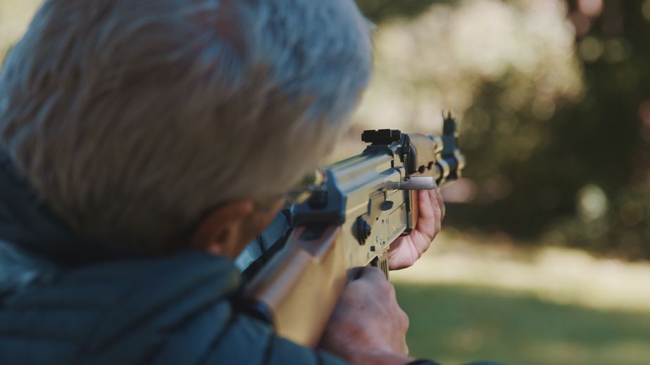 Elderly gray haired man holding a gun in his hands