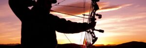 Bowhunter taking shots underneath sunset