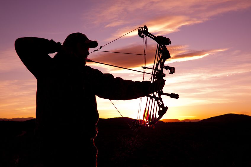 Bowhunter taking shots underneath sunset