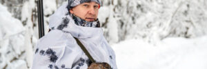 Male hunter worried about frostbite out in a cold, winter forest