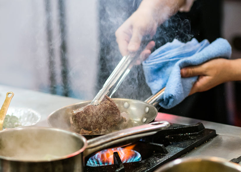 Man cooking buffalo meat in kitchen