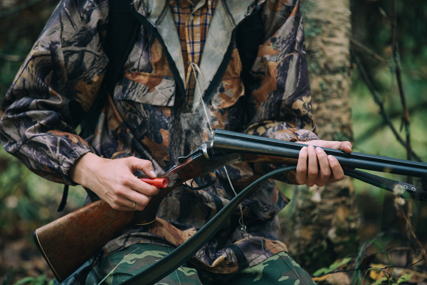 Hunter loading rifle in woods