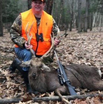 Male hunter holding up the antlers of a Sika Deer