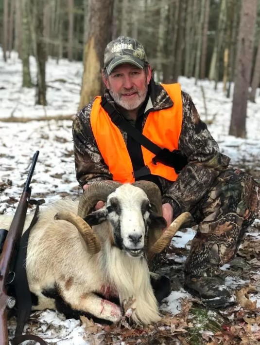 Hunter in winter posing with Corsican Ram