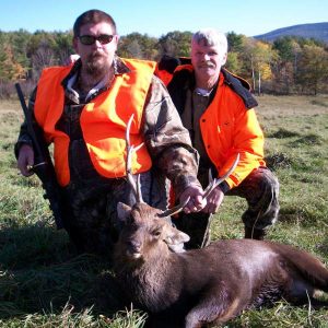 Two hunters posing with a sika deer