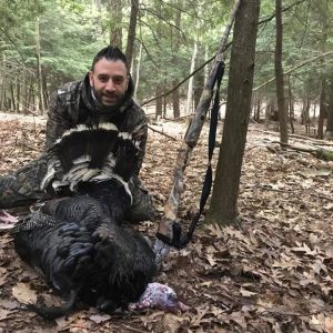 Man posing with hunted turkey