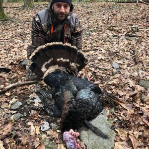 Man posing with hunted turkey