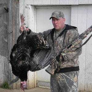 Man posing with hunted turkey