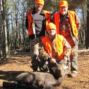 Three hunters posing with a sika deer they caught at Tioga Ranch